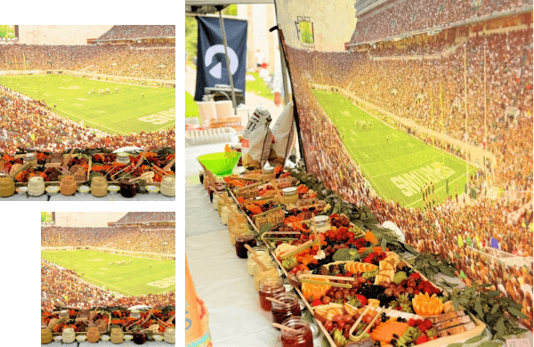 A buffet table with a variety of food items is set up against a backdrop of a crowded stadium during a sports event.